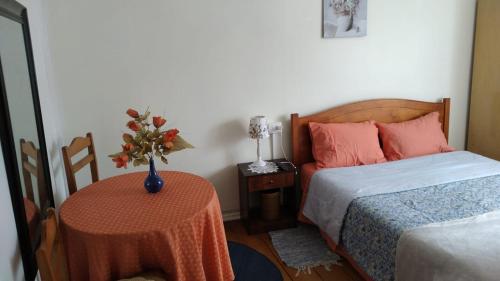蒙特港Hostal Patrimonial Angelmó的一间卧室配有一张床和一张桌子,上面有花瓶