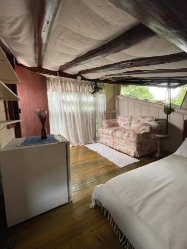 瓜尔达恩巴Hostel Antônio Pescador Guarda do Embau的一间卧室配有一张床和一个沙发