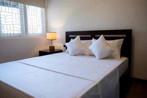 科伦坡Avega Urban - Colombo 07的卧室内的一张带白色床单和枕头的床