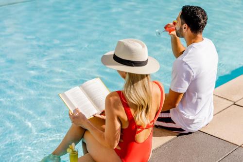 圣地亚哥奥米尼圣迭戈酒店的坐在游泳池旁的男人和女人