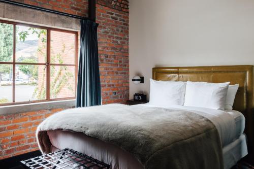 圣路易斯-奥比斯保格拉纳达酒店兼小酒馆的一间卧室设有一张带砖墙的大床