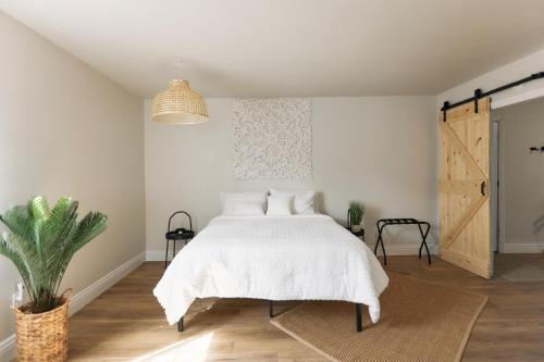 约书亚树Minutes to JT National Park, Hot Tub & Game Room的卧室配有白色的床和盆栽植物