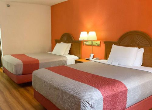 Cardinal Court诺默尔 - 布卢明顿地区6号汽车旅馆的橙色墙壁的酒店客房内的两张床