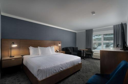 坎卢普斯Prestige Kamloops Hotel的配有一张床和一把椅子的酒店客房