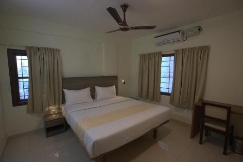 班加罗尔Elysian Grand Hotel的一间卧室配有一张床和吊扇