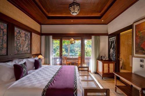 乌布Puri Saraswati Dijiwa Ubud的一间卧室配有一张大床和一张桌子