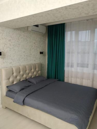 阿拉木图Молодежный的一间卧室配有一张带绿帘的大床