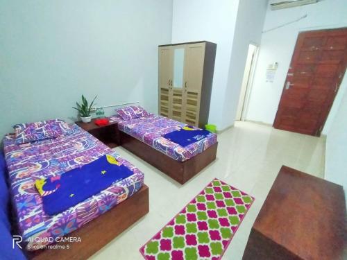SintangWismaALAS Syariah Guesthouse的一间设有两张床和一张桌子的房间