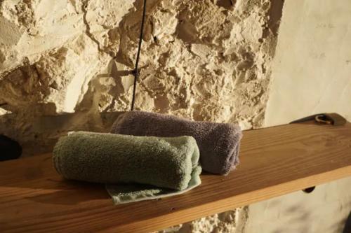 蓬塔戈尔达Tiny House Vogelnest的石墙旁木架上的两条毛巾
