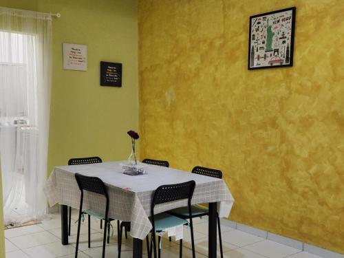 巴特沃思Al Irfan Homestay Tmn SgDua Utama的餐桌、椅子和黄色墙壁