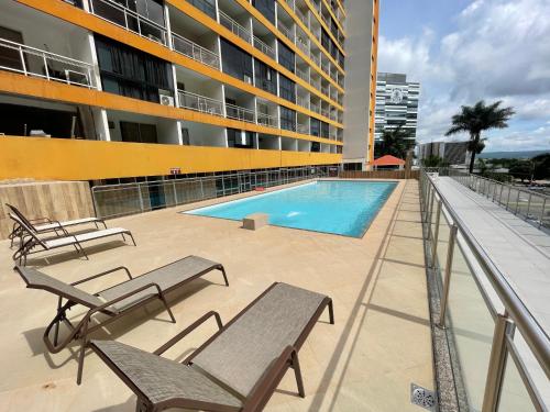 巴西利亚MIX APART Hotel的一个带长椅的游泳池和一座建筑