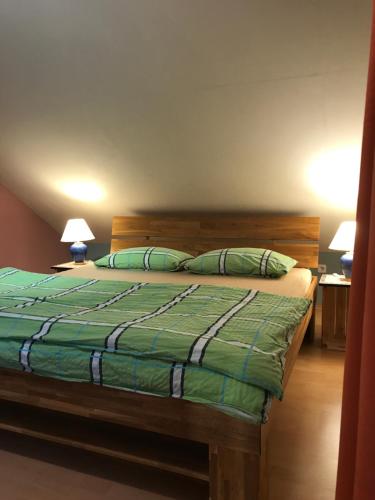 魏斯基兴Ferienwohnung Maxima的一间卧室配有一张带绿色被子的床和两盏灯。