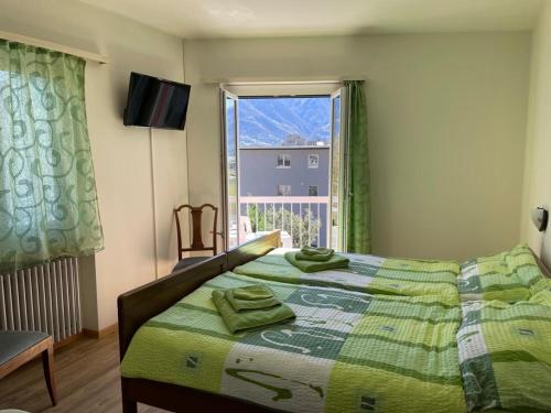 戈尔多拉Ristorante Gordolese con alloggio的一间卧室配有一张带绿色床单的床和一扇窗户。