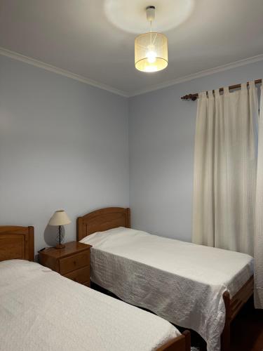 卡尼萨尔Apartamentos Amarelo的一间卧室设有两张床、一盏灯和一扇窗户。