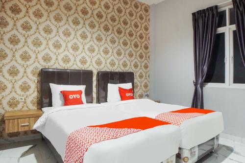 棉兰SUPER OYO Capital O 92066 Papakoel Hotel & Cafe的卧室配有带红色枕头的白色床
