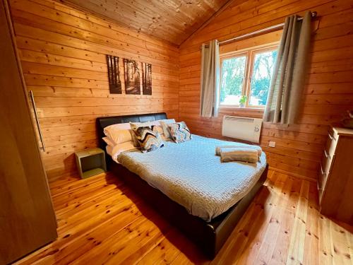 南塞尔尼Lake Pochard, Oak Lodge的木制客房内的一间卧室,配有一张床