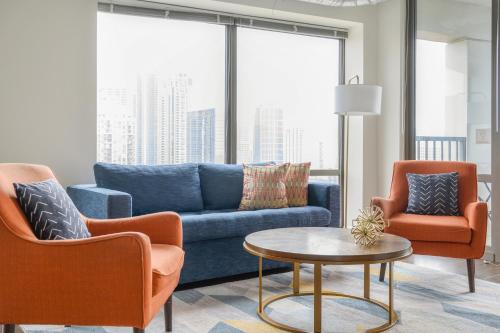 芝加哥Kasa South Loop Chicago的客厅配有蓝色的沙发和两把椅子