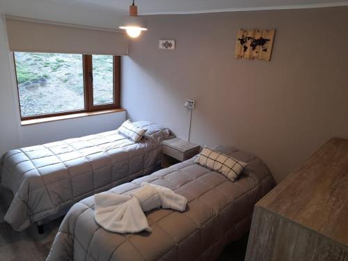 卡薇亚惠Del Sendero Caviahue的客房设有两张床、一张桌子和一扇窗户。