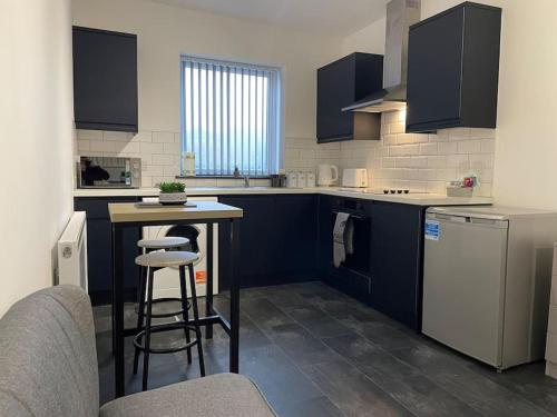 特伦特河畔斯托克Modern Apartment With En-suite & Private Kitchen的厨房配有蓝色橱柜、桌子和凳子