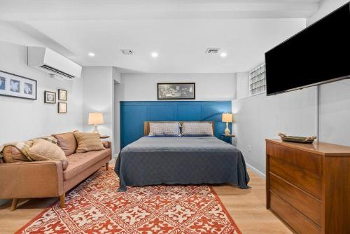 匹兹堡Trendy & Hip South Side Studio Walk to Downtown的一间卧室配有一张床、一张沙发和一台平面电视。