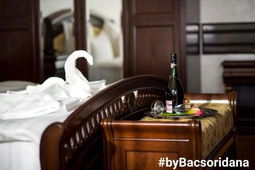 TecuciHotel Bacsoridana的床上的一瓶香槟和一盘水果