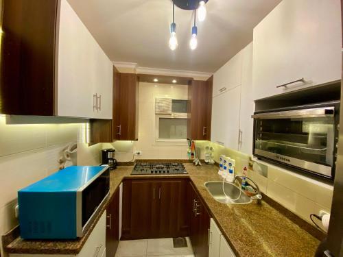 开罗Cozy 2BR Apartment in Maadi的厨房配有水槽和炉灶 顶部烤箱