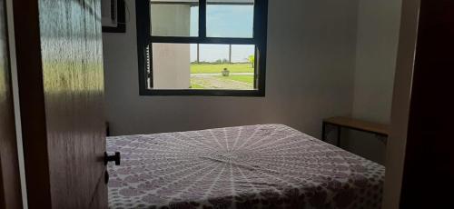 里约达欧特拉斯Chalé Pé na Areia em Rio das Ostras的客房设有窗户和一张带桌子的床。