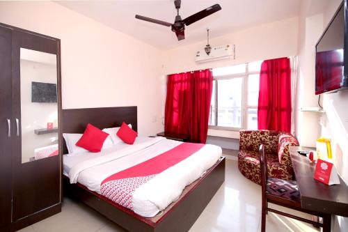 贾巴尔普尔OYO Hotel Dwarika Inn的一间卧室配有一张床、一张书桌和红色窗帘