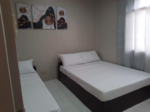 长滩岛Tresha Lance Apartelle的小客房内的两张床,配有白色床单
