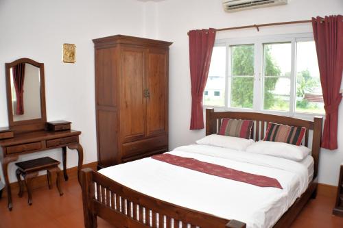 清迈P and A Thai Lanna Resort的一间卧室配有一张床、梳妆台和镜子