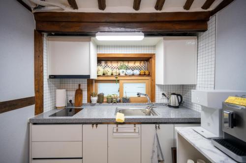 大邱Hanok1942的厨房配有白色橱柜和水槽