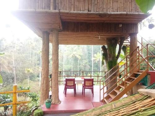 ChegātKalidasa Tree House and Villa, Wayanad的一个带椅子和桌子的大型木制门廊