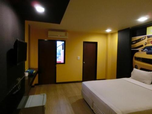 Ban KoNewYork Suite Hotel的一间卧室设有床铺、电视和黄色的墙壁