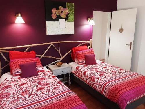 TravaillanLa Bonbonne en Provence的紫色墙壁客房的两张床