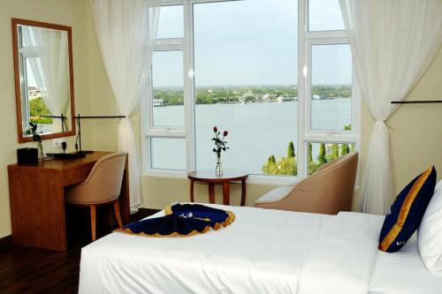 永隆Khách sạn Sài Gòn Vĩnh Long的一间卧室配有一张床、一张书桌和一个窗户。