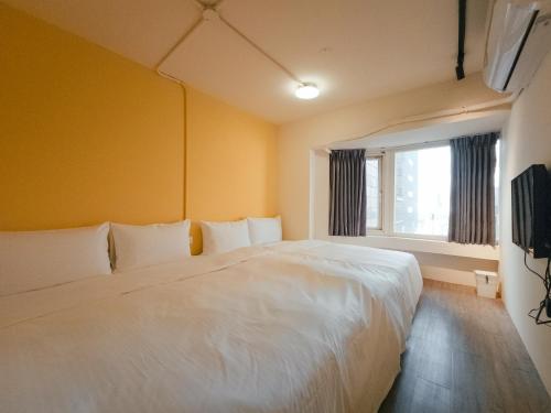 台北台北栈旅店的卧室配有白色的床和窗户。
