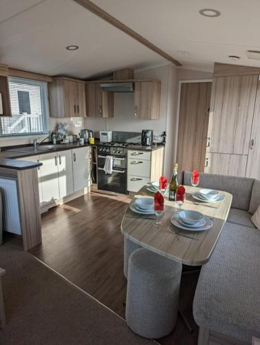 韦茅斯Sleeps 6 Modern and bright Caravan Littlesea Haven Weymouth的一间带木桌的厨房和一间带桌椅的厨房