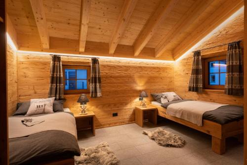 贝韦Engadin Chalet - Private Spa Retreat & Appart -St Moritz - Val Bever的配有木墙和窗户的客房内的两张床