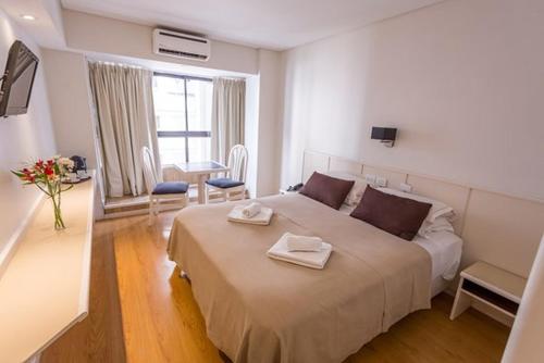 马德普拉塔Hotel Dion的一间卧室配有一张大床和两条毛巾