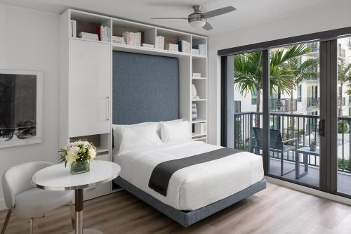 西棕榈滩AKA West Palm的一间卧室配有一张床铺和一张桌子,并设有一个阳台