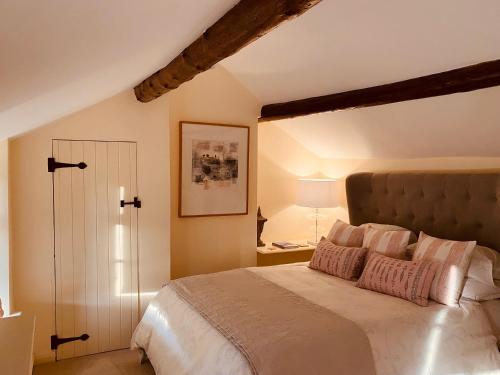奇平卡姆登Vine Cottage的卧室配有一张带粉红色枕头的大床