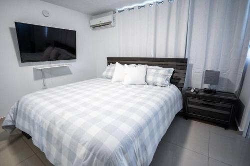 多拉多Aquaville Dorado Moderna Villa 1的一间卧室配有一张带 ⁇ 子毯子的床和一台电视