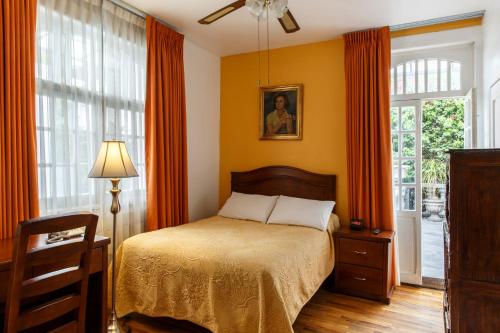 墨西哥城卡萨冈萨雷斯酒店的一间卧室配有带橙色窗帘的床和窗户