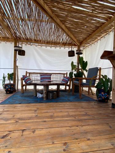 江比阿Jambiani Backpackers Hostel的帐篷内带长椅和桌子的庭院
