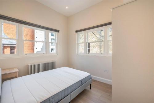 泰晤士河畔里士满Apartments in the heart of Richmond, London的一间卧室设有一张床和两个窗户。