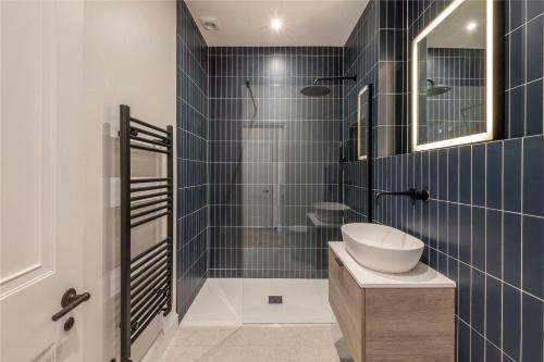泰晤士河畔里士满Apartments in the heart of Richmond, London的浴室设有水槽和蓝色瓷砖淋浴。