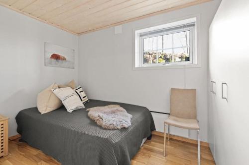 阿斯克尔Pretty appartment close to Oslo的一间卧室设有一张床、一个窗口和一把椅子
