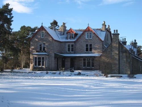 卡布里奇Dalrachney Lodge的一座大砖房,地面上积雪