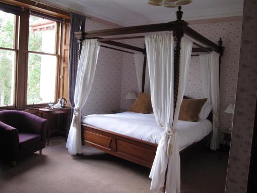 卡布里奇Dalrachney Lodge的卧室配有带白色窗帘的天蓬床