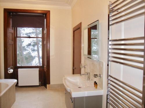 卡布里奇Dalrachney Lodge的一间带水槽和浴缸的浴室以及窗户。